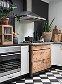 Kitchen with black and white chequerboard floor, wooden elements and plants