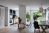 Open-plan kitchen with black and white tiled floor and dining area with black chairs and hanging lamps