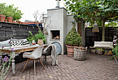 Cosy patio area with outdoor fireplace, wooden table and plants