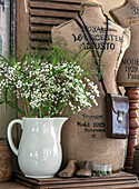 Vintage dressmaker's dummy with leather bag and bouquet of flowers in ceramic vase