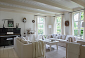 Living room with light-coloured sofas, piano and large windows