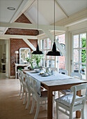 Dining area with wooden table, white wooden beams and black hanging lamps