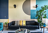Wohnzimmer mit geometrischer Wandgestaltung und Ledersofa