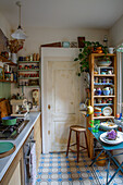 Country kitchen with open wooden shelves, patterned tiled floor and plant