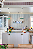 Modern country house kitchen with light grey cabinets and wooden wall panelling