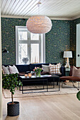 Living room with floral wallpaper, sofa, coffee table and white pendant light with feathers