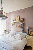 Bedroom with pink-coloured wall, wall shelf and vintage decor