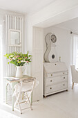 White country house furniture in a light-coloured room with a bouquet of flowers in a vase