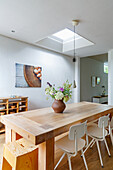 Wooden dining table with bouquet of flowers, skylight