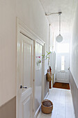 Narrow hallway with white doors, wooden floor and basket