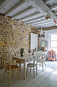 Dining room with rustic stone wall, light-coloured furniture and floorboards