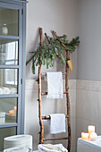 Rustic wooden ladder with fir branches and towels in the bathroom