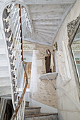 Historic staircase with wooden banister and religious statue