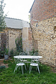 White metal table with matching chairs in rustic garden area