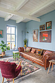 Vintage leather sofa in living room with plants and blue painted walls