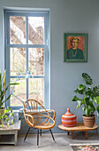 Bright living room with wicker armchair, plants and paintings