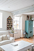 Bright country-style living room with blue metal cupboard and wooden beams