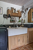 Country kitchen with rustic wooden cupboards and white ceramic sink