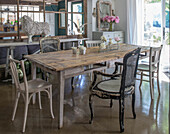 Dining table with various antique chairs in a rustic room