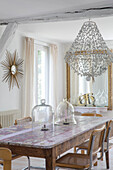 Dining room with rustic wooden table, glass canopies and beaded chandelier