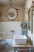 Vintage bathroom with washbasin on a rustic wooden table and decorative lifebuoy on the wall