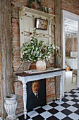 Narrow wall table with bouquet of flowers and vintage decoration in front of brick wall