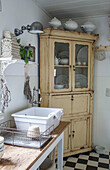 Shabby chic country kitchen with antique buffet cabinet and black and white chequerboard floor