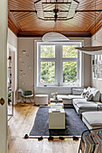 Living room with wooden ceiling, grey corner sofa and black carpet