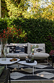 Modern patio with white sofa, patterned cushions, outdoor rug and coffee tables