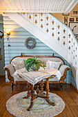 Sitting area under stairs with antique sofa and lace cover on wooden table