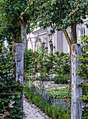 Picturesquely planted garden path with roses and rose arch