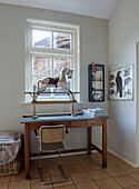 Desk with old rocking horse in front of window