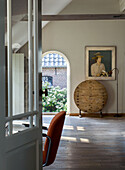 Open-plan living area with wooden floorboards, office chair and artwork on the wall