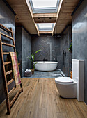 Bathroom with freestanding bathtub, skylight, wooden and tiled floor