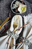 Herbstliche Tischdekoration mit goldfarbenem Besteck und Serviettenringen aus Flechten