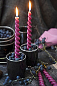 Kerzenständer mit frischen Schlehenbeeren gefüllt