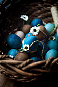 Easter eggs in shades of blue and natural colours in a rustic basket