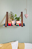 DIY-Wandregal dekoriert mit Pflanzen und Kerzen mit einem Herz-Anhänger