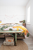 Bright bedroom with floral bed linen and rustic bed bench