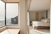 Bedroom with sea view and large corner window, wooden floor and textiles in light colours