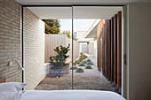 Blick vom Schlafzimmer auf minimalistischen Innenhofgarten mit Kiesweg