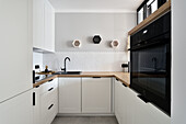 Moderne Küche mit weißer Einrichtung und Holzarbeitsplatte