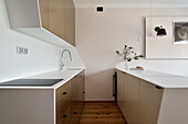 Moderne Küchenzeile in Weiß mit Holzboden und minimalistischer Beleuchtung