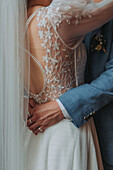 Braut im bestickten Kleid und Bräutigam im blauen Anzug umarmen sich