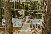 Outdoor wedding area with white chairs and bunting in the forest