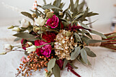Brautstrauß mit Rosen und Eukalyptuszweigen auf Tischplatte