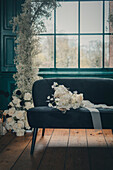 Upholstered bench with white bridal bouquet in front of window with green frame
