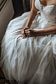Braut in weißem Spitzenkleid mit Tüll sitzt