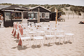 Weiße Stühle am Strand, Strandhütte und Dünen