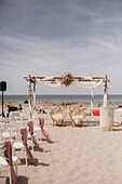 Boho-style wedding ceremony with white decorated alter on the beach